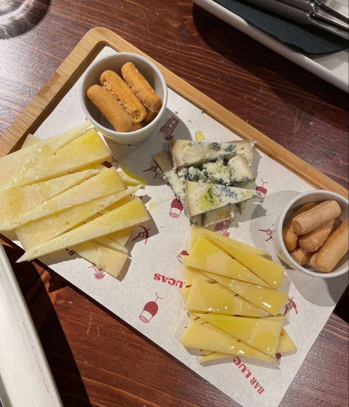Tabla de quesos con miel y palitos sobre papel BAR LUCAS